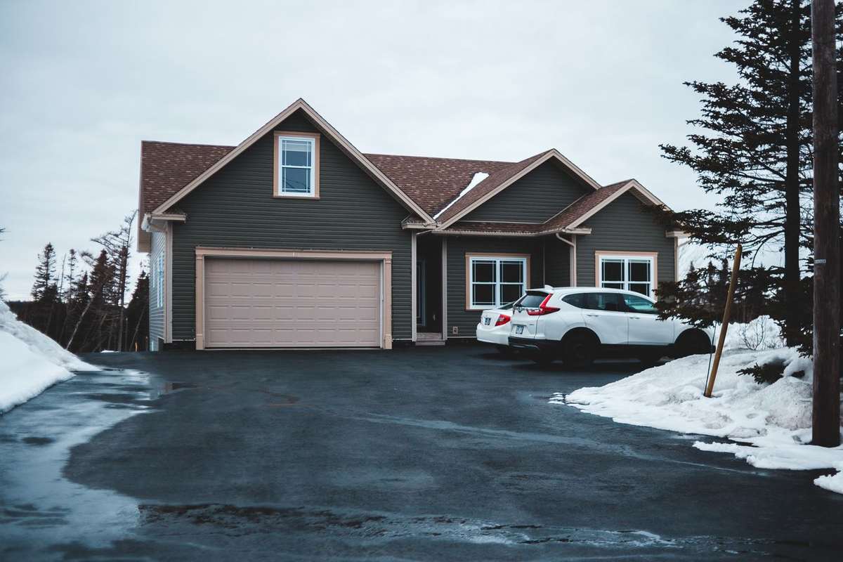 A house with a dark, freshly sealed driveway after snow