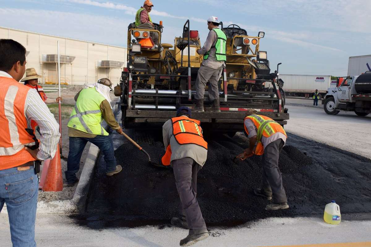 Paving crew spreading hot asphalt behind a paver