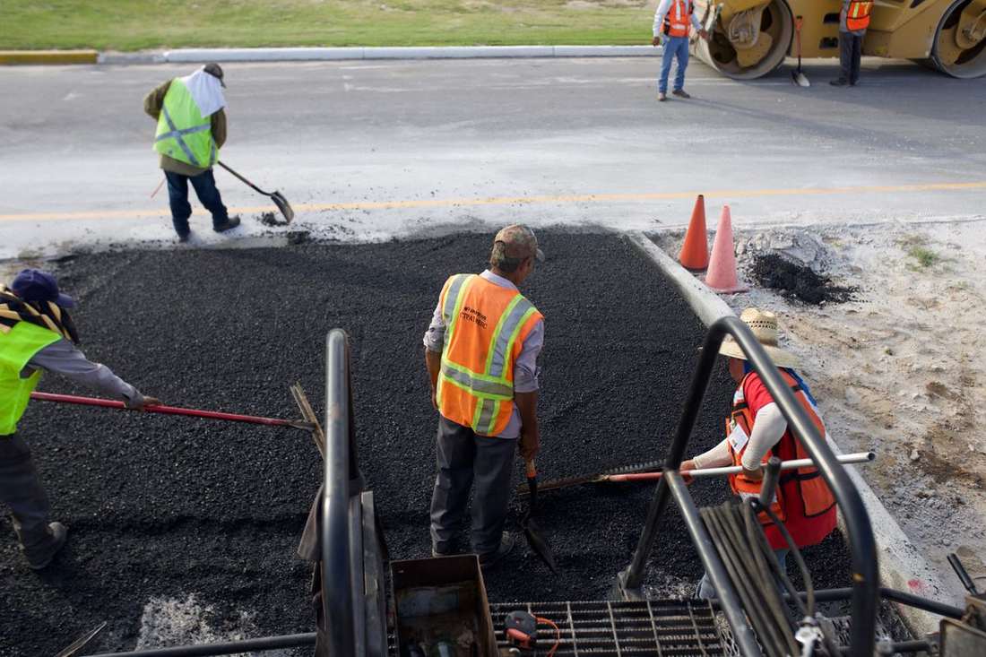 Crew raking fresh hot-mix asphalt into place